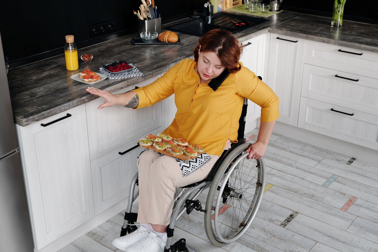 A woman in a wheelchair prepares food in a contemporary kitchen, showcasing everyday independence.